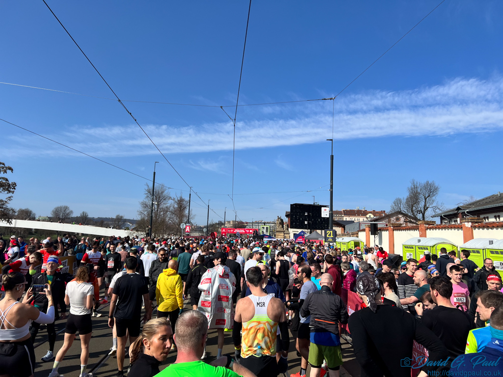 A large number of runners facing away from the camera, towards a start gantry.