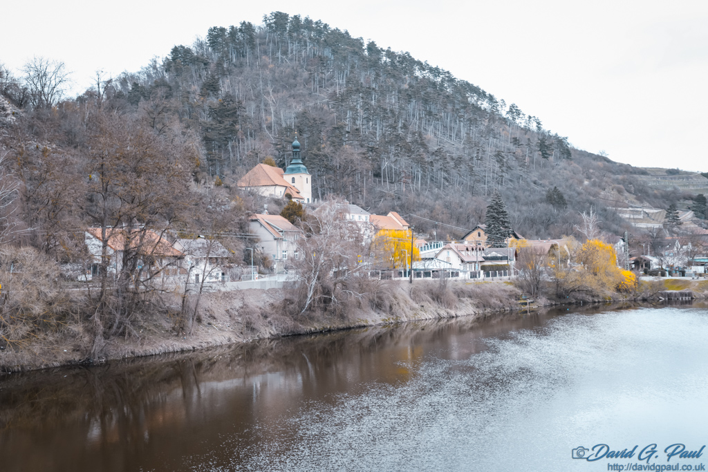 Some buildings just visible through bare trees on the other side of the river.