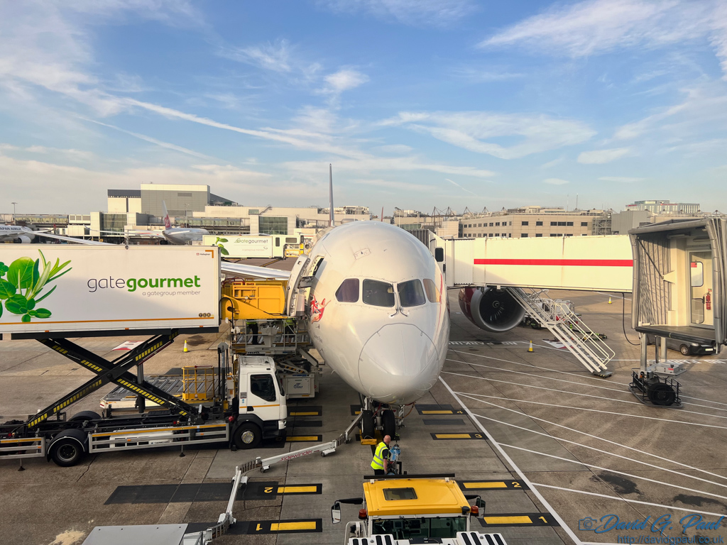 A 'gate gourmet' truck is parked aginst an aircraft with a skygate also extended towards it on the other side