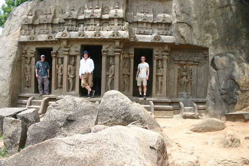 Three males stand in entranceways to a temple dedicated to Vishnu in Mahabalipuram.