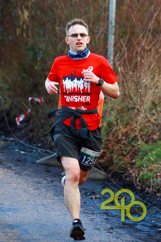 A male wearing red and black, running on the road