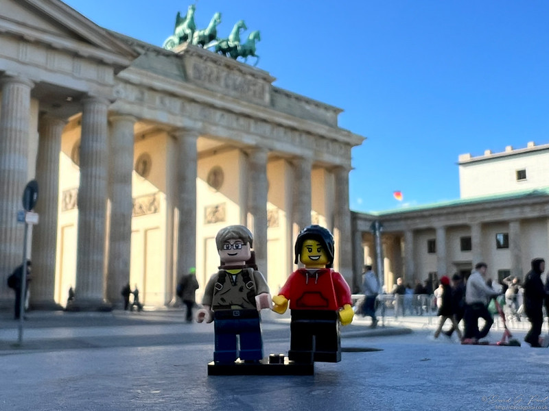 Two LEGO minifigures standing in front of the Brandenburg Gate in German