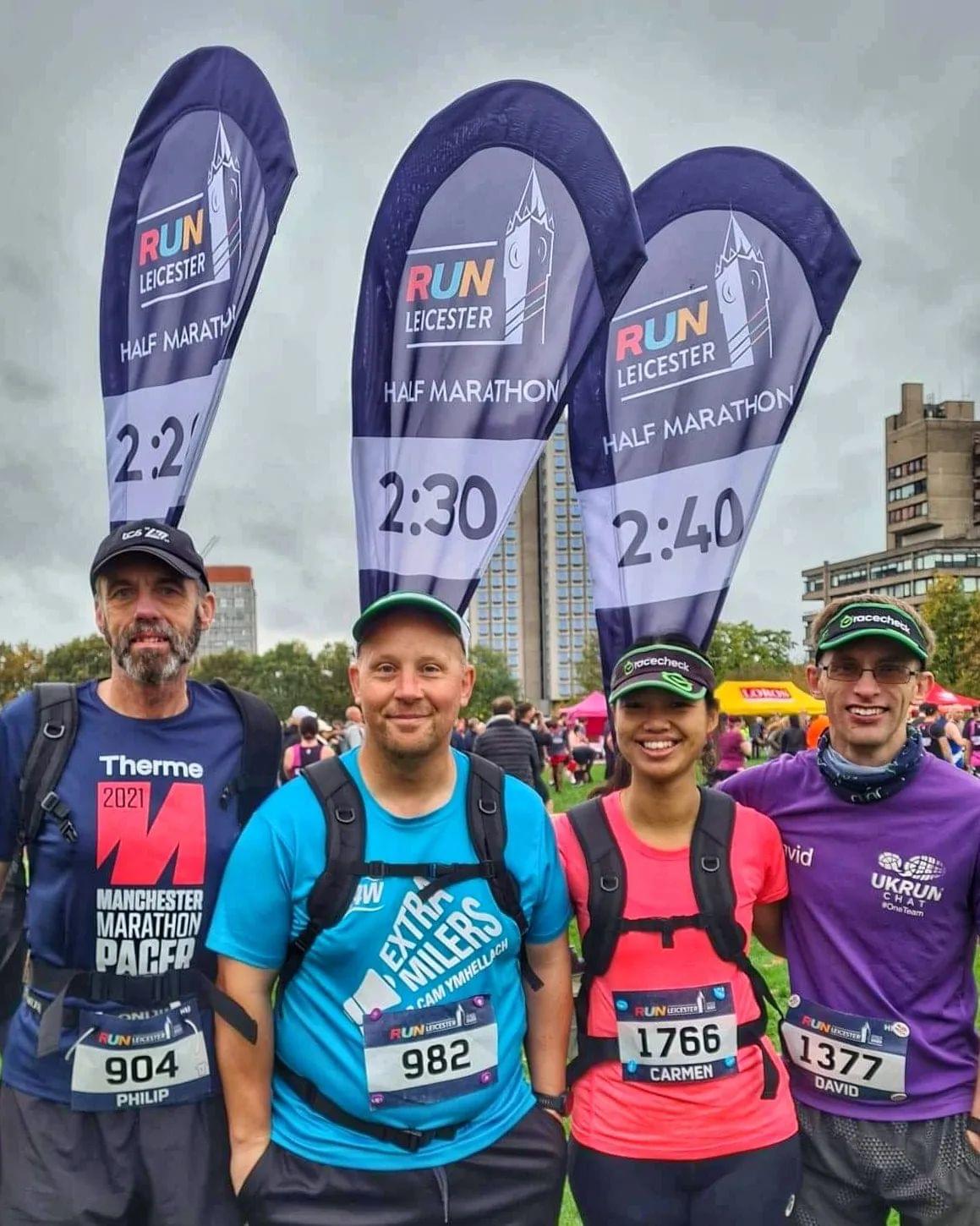 Two male runners with pacing flags, a female runner with pacing flag, and a male runner